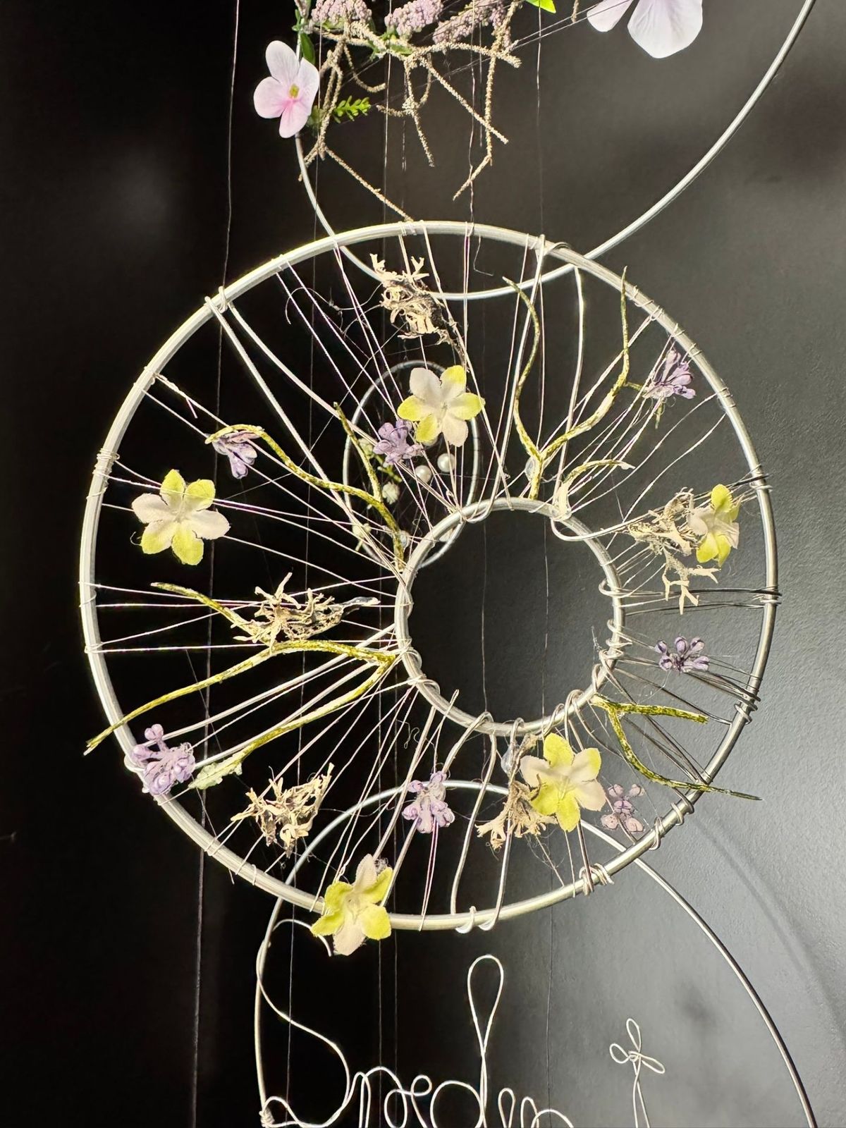 Detailansicht einer floralen Drahtring-Installation mit Blüten