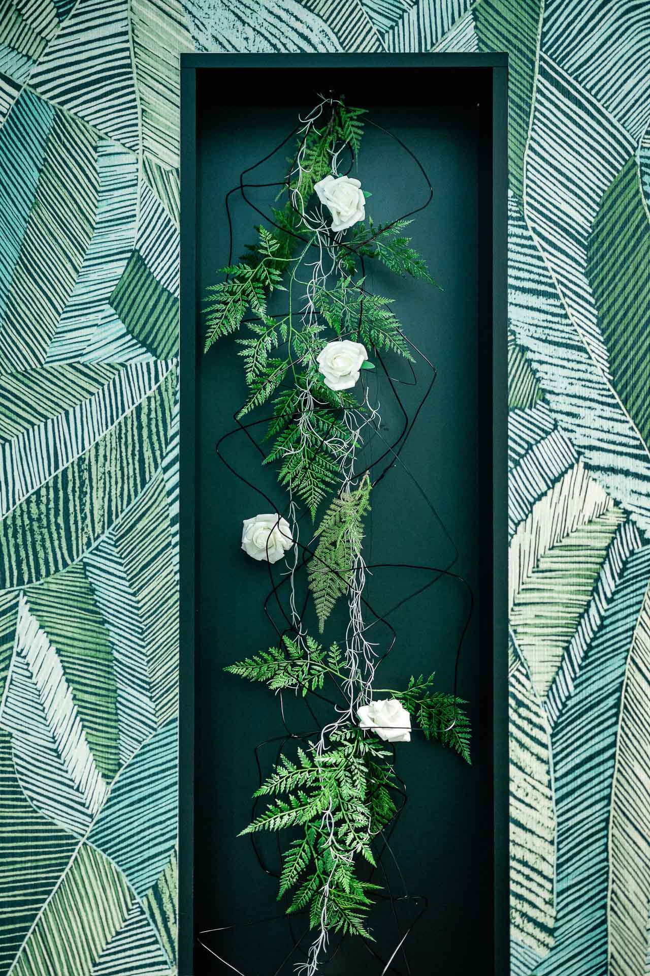 Vertikale florale Wandinstallation mit Farnen und weißen Rosen